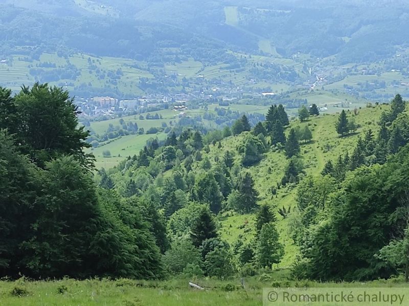 Hilly landscape around Hriňová with green gardens and extensive forest area.