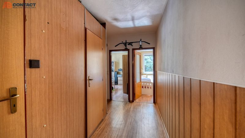 A hallway with walls featuring a wooden decor in a 4-room apartment, with visible doors to the rooms.