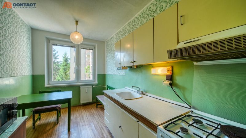 A kitchen in a 4-room apartment with a wooden decor floor and green walls.