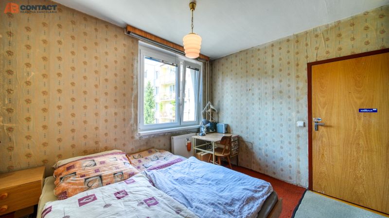 Bedroom in a 4-room apartment with a bed, table, wallpaper, and doors with a wooden decor.