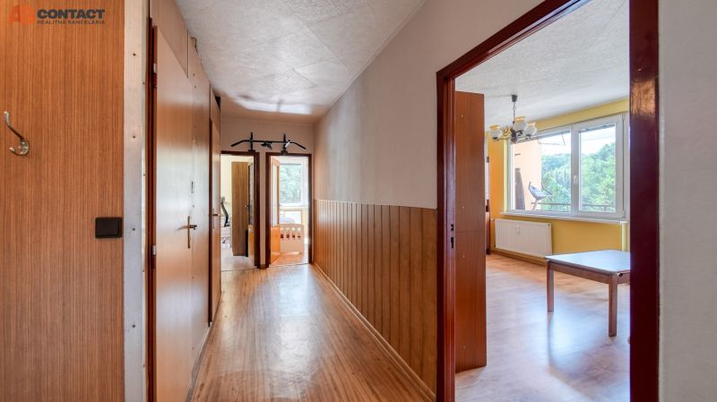 A hallway with a wooden decor floor in a 4-room apartment with entrances to the rooms.