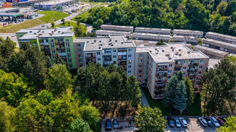 A view of residential blocks on Viestova Street in Myjava surrounded by greenery and a parking lot.