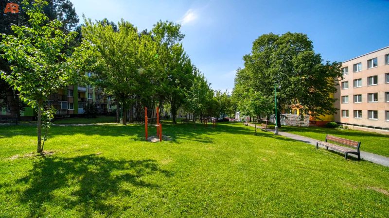 Greenery with benches and a walkway in front of the apartment buildings on Viestova Street in Myjava.