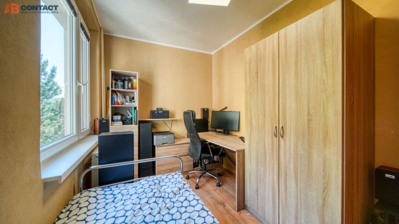 A room with a wooden floor decor, a bed, and a desk in a 4-room apartment.