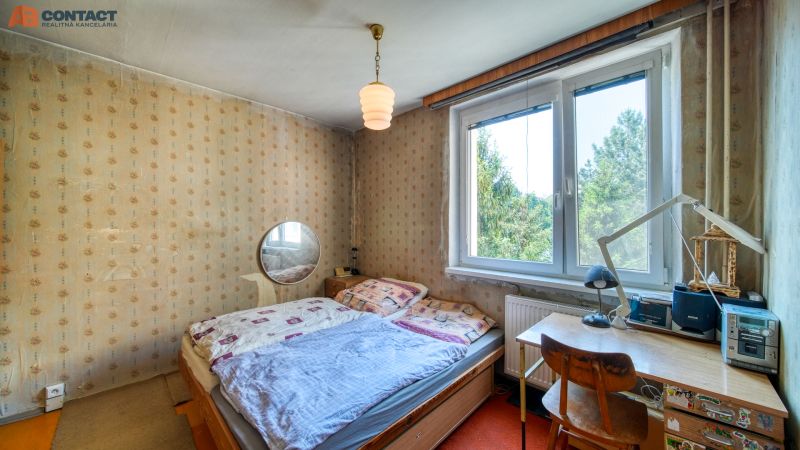 A bedroom with older furniture, wallpaper, and a window in a 4-room apartment.