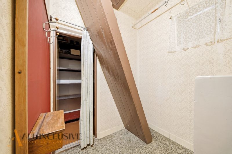 Storage space with a sloped roof in a family house with wallpapered walls.