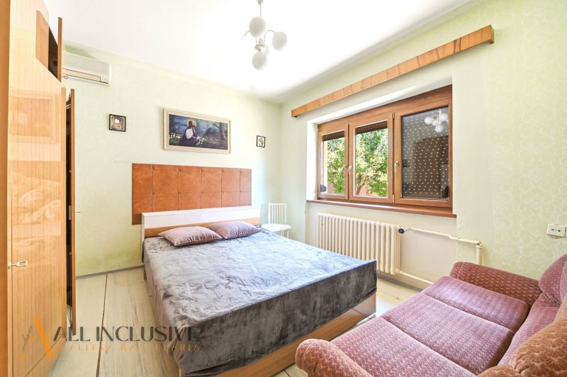 Bedroom with a large bed, sofa, and paintings in a family house.