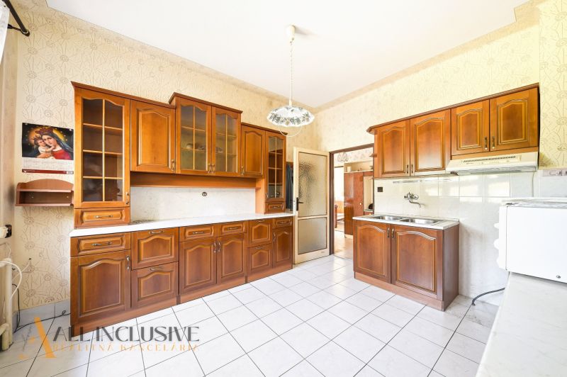 A kitchen in a family house with wooden cabinets and white tiles.