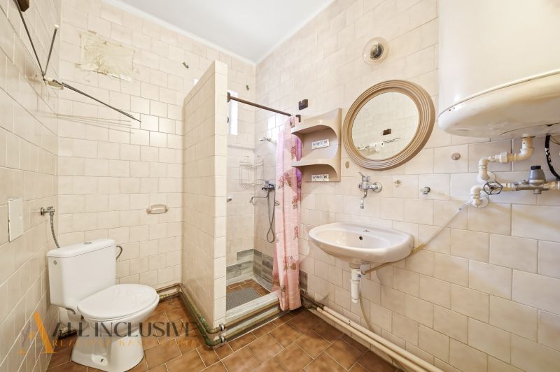 A bathroom in a family house with white tiles and a shower enclosure.