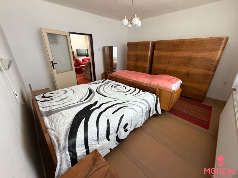 A bedroom in a family house with wooden wardrobes and a bed with a decorative cover.