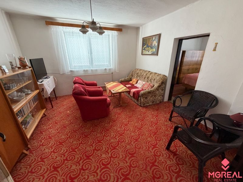 A living room in a family house with a red carpet, a sofa, and armchairs.