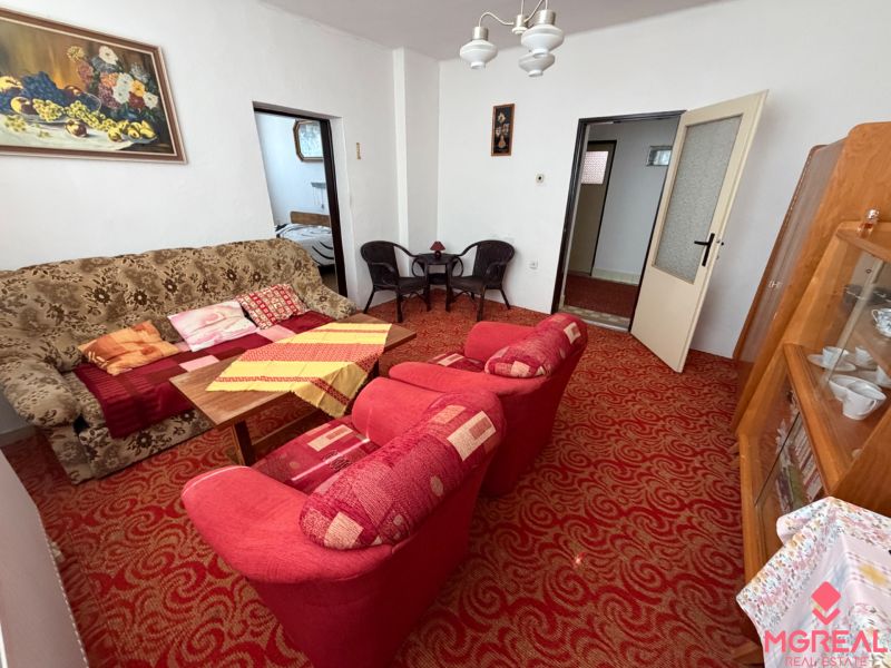Living room in a family house with a patterned carpet, sofa, and armchairs.