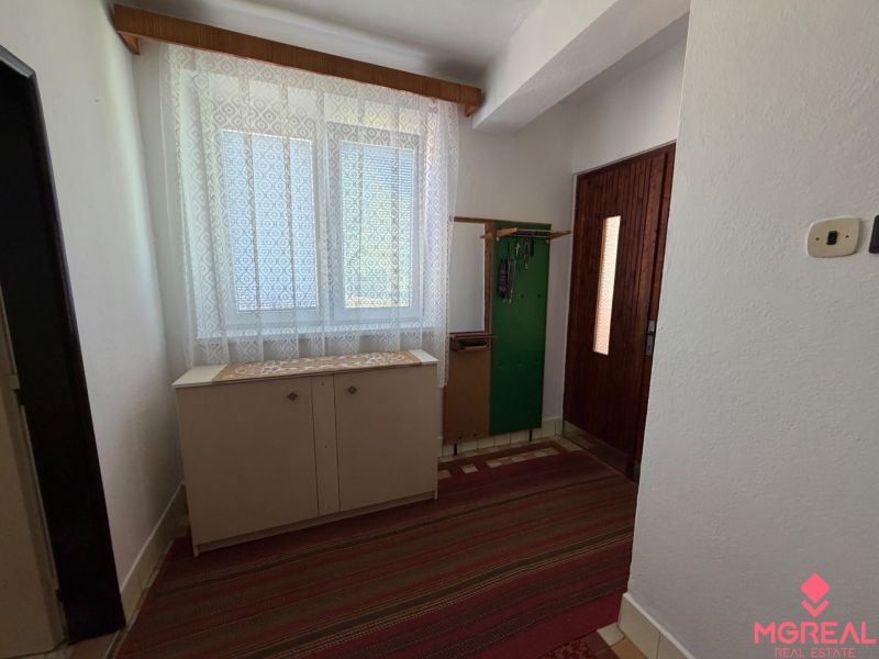 Entrance hallway in a family house with a shoe cabinet, coat rack, and patterned curtains.