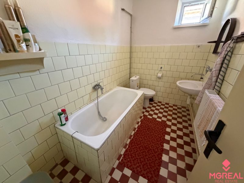 Bathroom with a bathtub, tiled walls, and a sink in a family house.