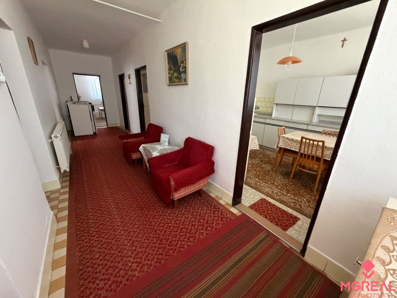 A hallway with carpets and a kitchen in a family house, furnished with stylish chairs and a table.