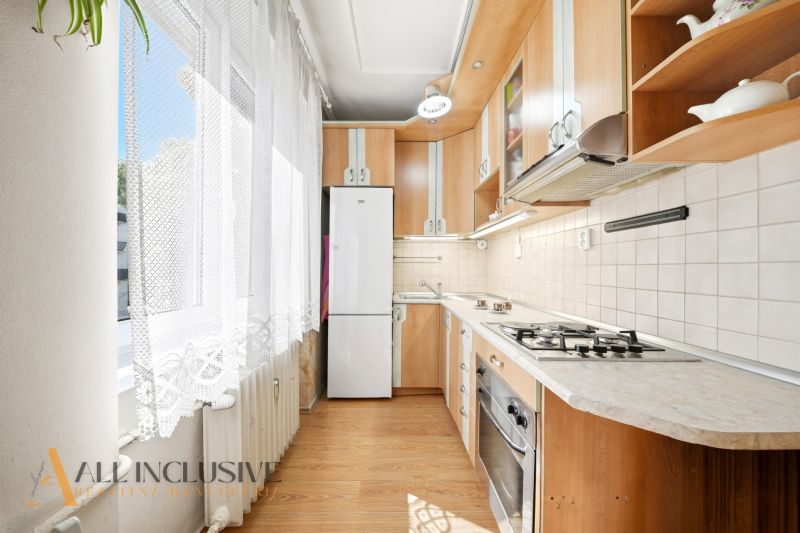 A kitchen in a 3-room apartment with a wooden decor floor and a kitchen unit.