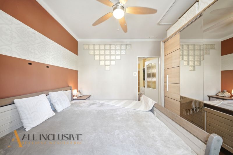 Bedroom with a built-in wardrobe and geometric decor in a 3-room apartment with a wood-patterned floor.