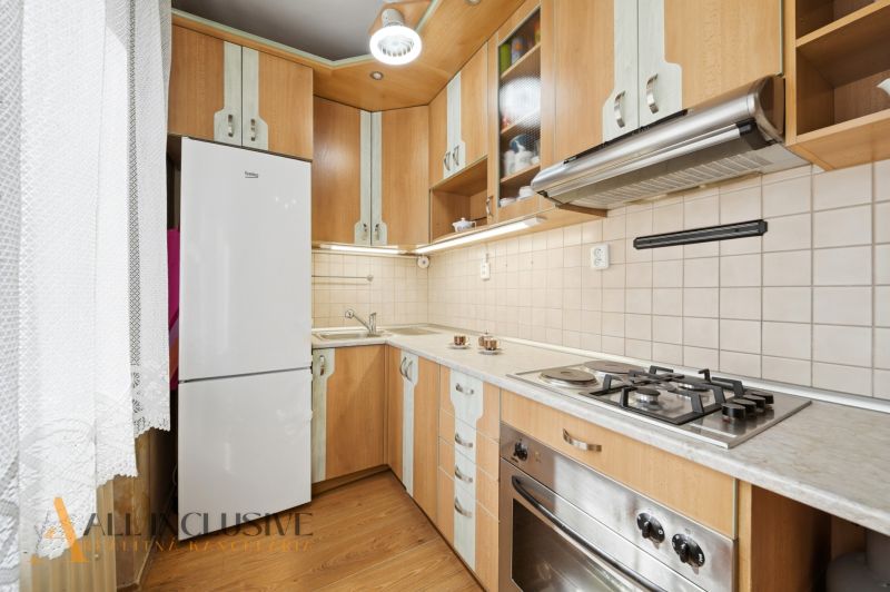 A kitchen unit in a 3-room apartment with a stove and a floor with a wooden decor.