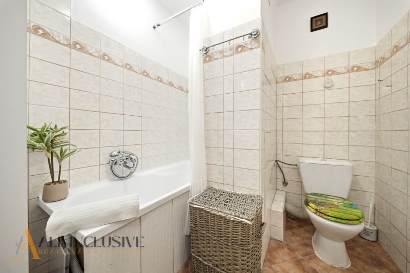 A bathroom in a 3-room apartment with a bathtub, a laundry basket, and decorative ceramics.