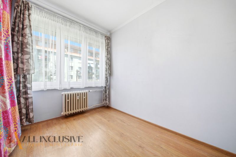 A room in a 3-room apartment with a wooden decor floor and a large window.
