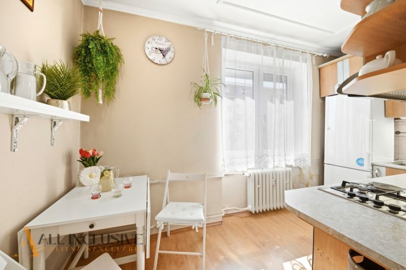 A bright kitchen in a 3-room apartment with plants and a wood-decor floor.
