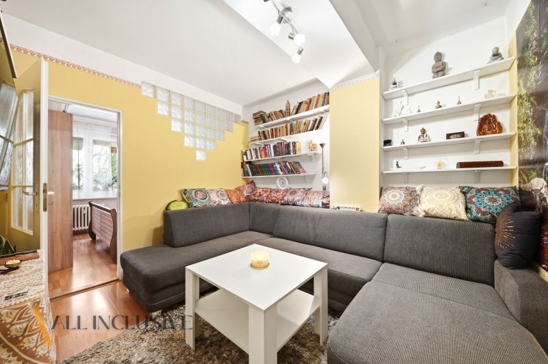 Living room with a sofa, shelves, and lots of cushions in a 3-room apartment.