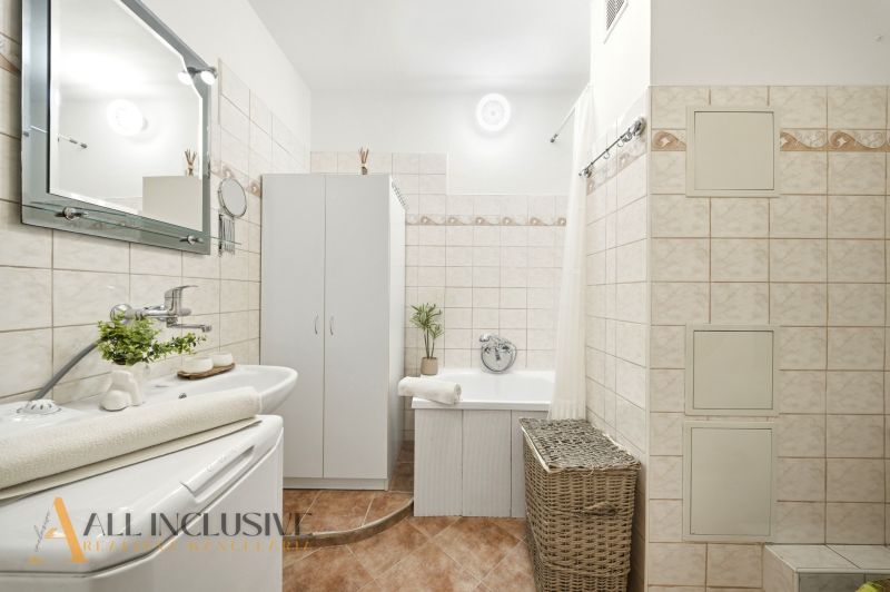 Bathroom with a bathtub, sink, mirror, and storage cabinets in a 3-room apartment.