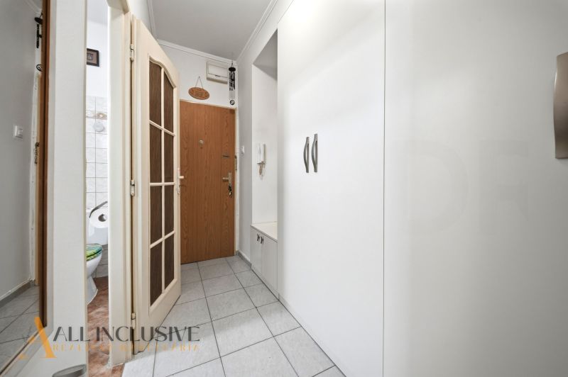 A hallway with white built-in furniture in a 3-room apartment, entrance doors, and tiles.