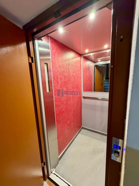 An elevator with red walls in a building; space for a 4-room apartment.