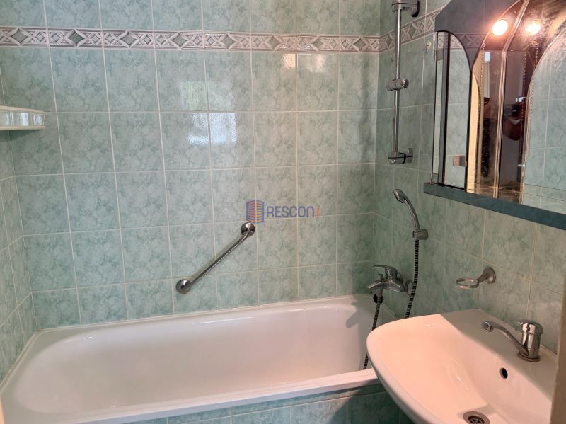 A bathroom with green tiles and a bathtub in a 4-room apartment.