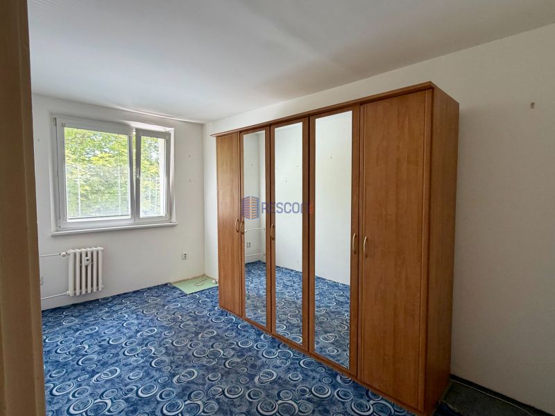A room with a wardrobe and a window, blue carpet, 4-room apartment.