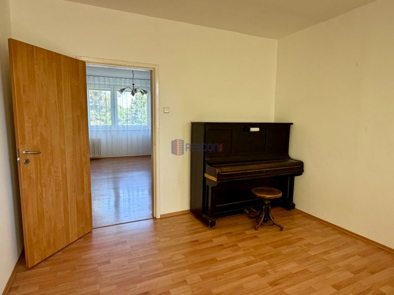 4-room apartment with a piano, wooden decor flooring, white wall, open doors.