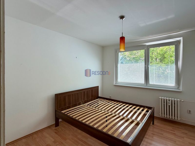 Bedroom in a 4-room apartment with a bed and a wooden decor floor.