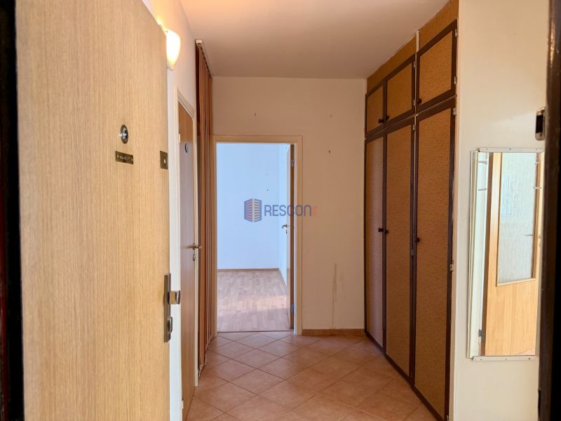 A hallway with a wardrobe and flooring in the decor of a 4-room apartment, light walls.