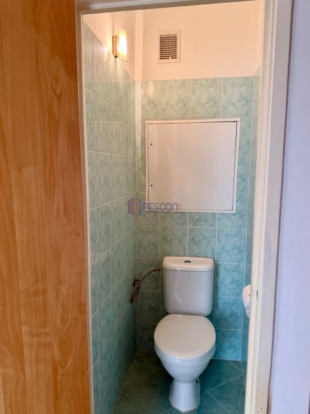 A toilet with blue tiles in a 4-room apartment.