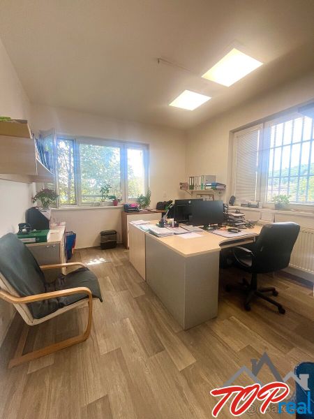 An office with a desk, chairs, and a wooden decor floor in commercial premises.