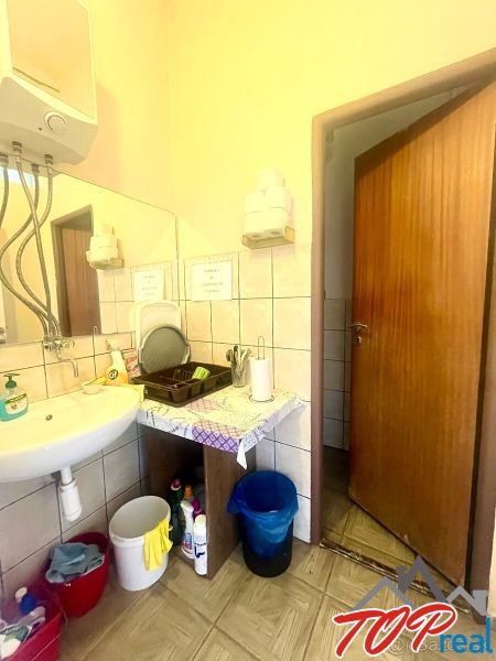 Bathroom with a sink, mirror, soap dispensers, and storage space.