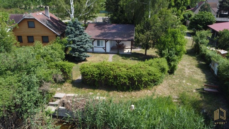 A cottage in Kopčany surrounded by greenery and trees, situated by the water.