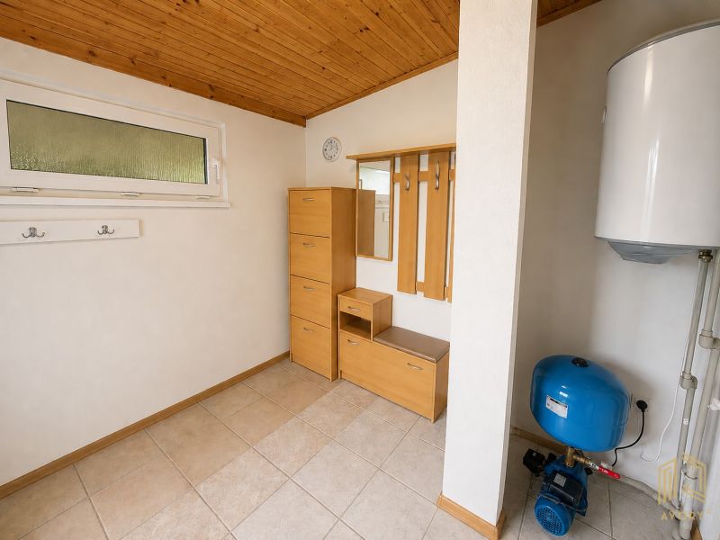 Interior of a cottage with storage furniture, a boiler, and tiled flooring.