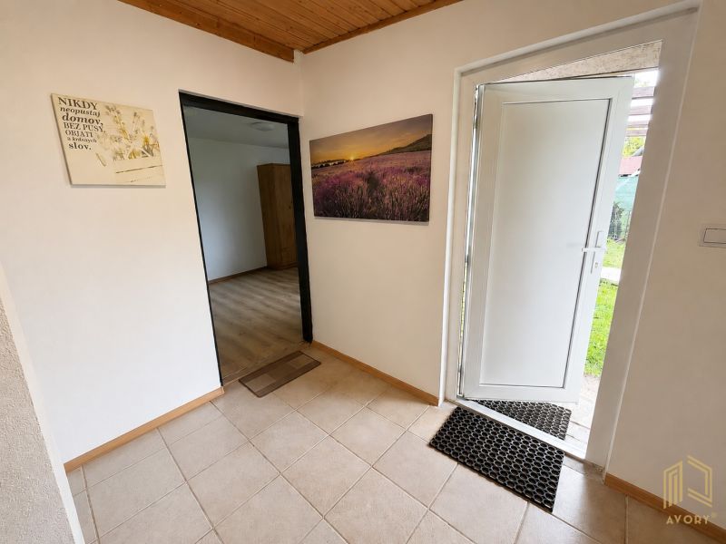 A cottage with tiles, open white doors, and a framed picture of flowers.