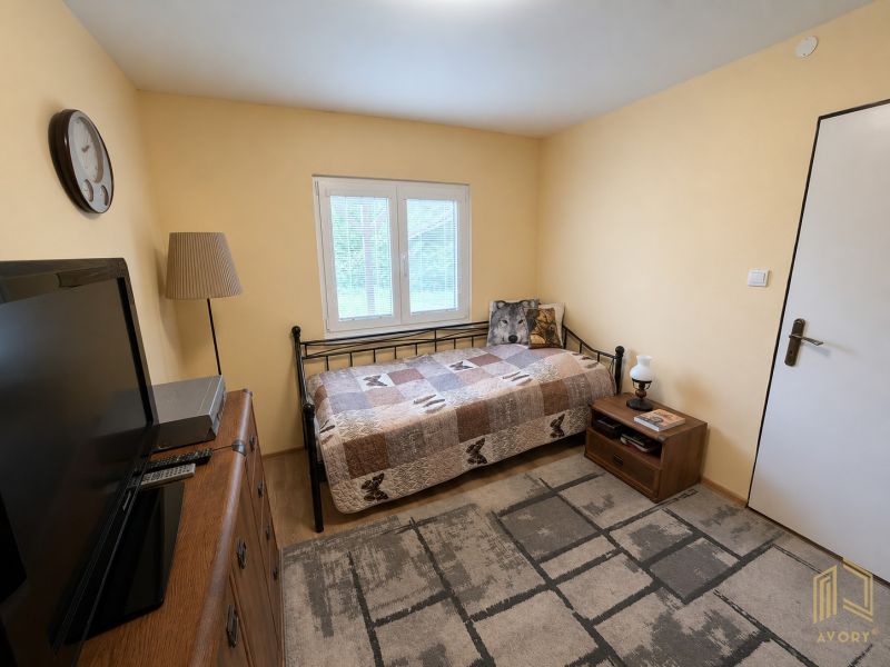 A room in a cabin with a bed, television, and wooden furniture.