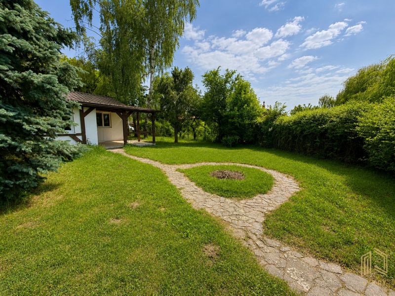 A cottage in Kopčany surrounded by greenery with a landscaped garden and an access path.