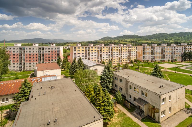 A view of the apartment buildings from Brezno on 9th May Street, surrounded by greenery and mountains.