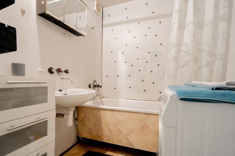 A bathroom with a bathtub, sink, and washing machine in a 3-room apartment.