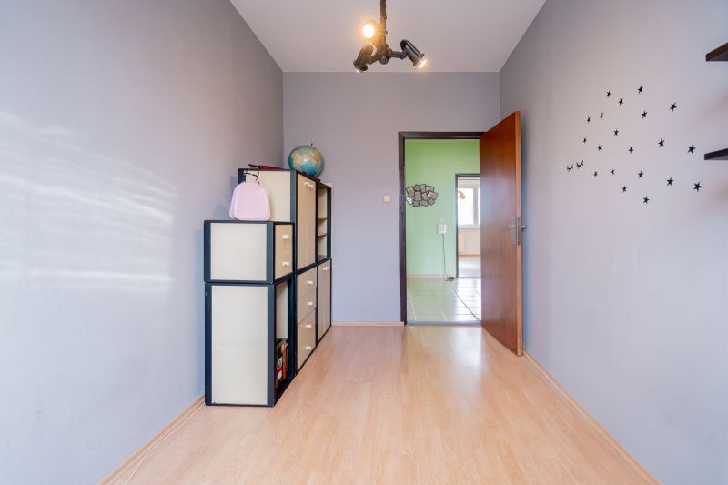 A room in a 3-room apartment with a wooden decor floor and wall decoration.