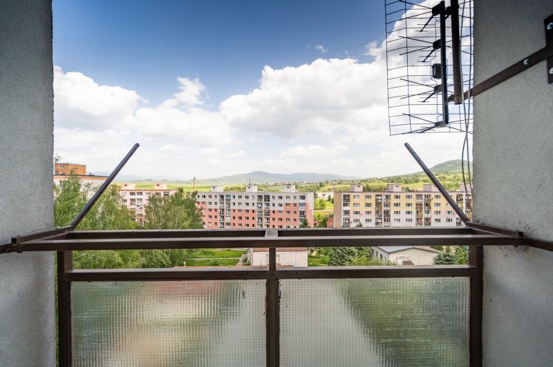 View from a 3-room apartment on 9th May Street in Brezno with apartment buildings and nature.