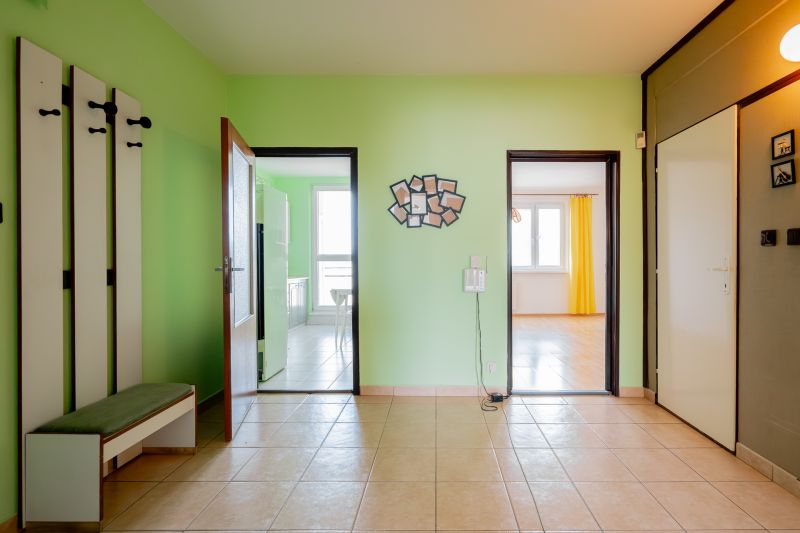 Interior of a 3-room apartment with tiles and light green walls, doors to the kitchen and living room.