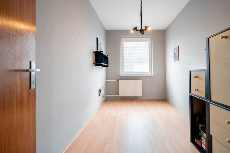 A room with a wooden floor decor, a window, and wall shelves in a 3-room apartment.