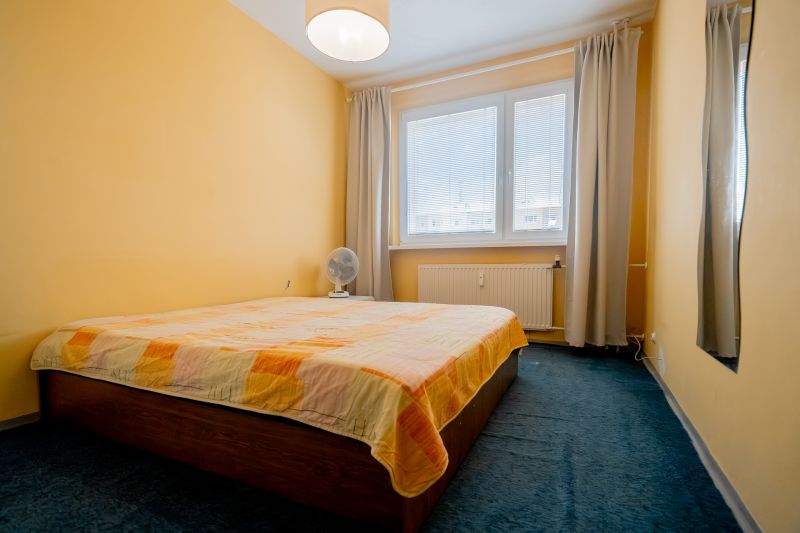 Bedroom in a 3-room apartment, with a double bed and yellow walls, blue carpet.