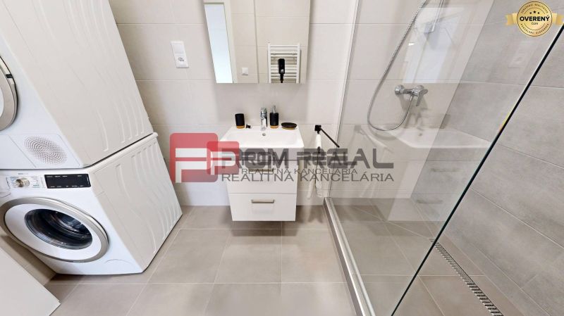 Bathroom in a 3-room apartment with a sink, shower, and washer with dryer.